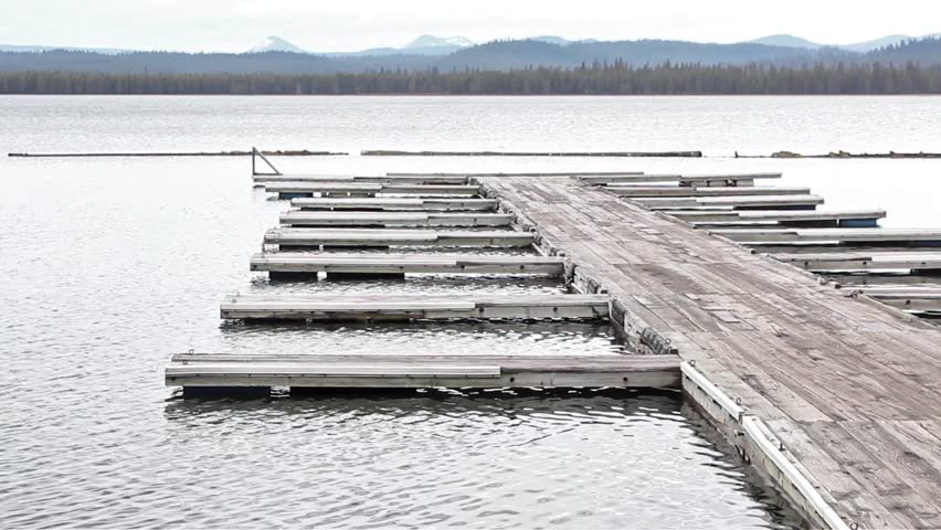 Water rippling under empty lake dock mountain background