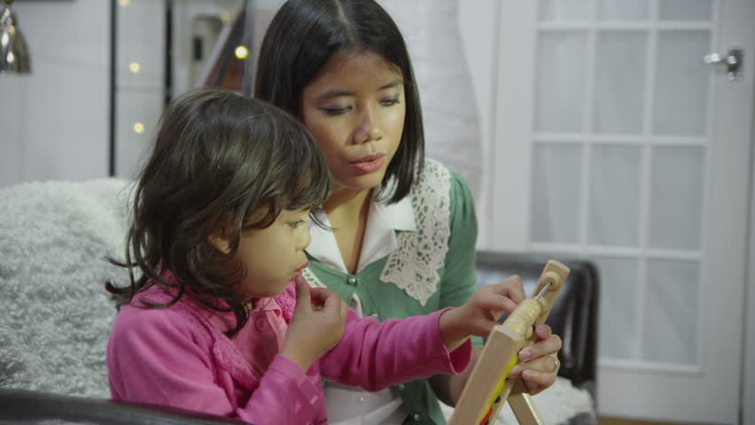 Cute little girl is learning to count on an abacus and enjoying a snack at the same time. In slow motion.