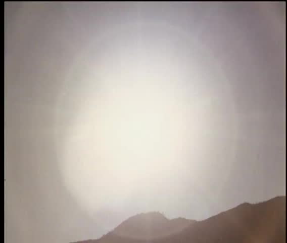 Bright sun shining on top of a mountain range at midday