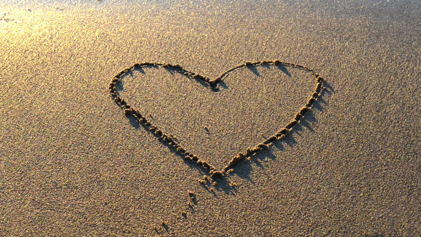 Heart drawn on the beach sand with sea foam and wave 