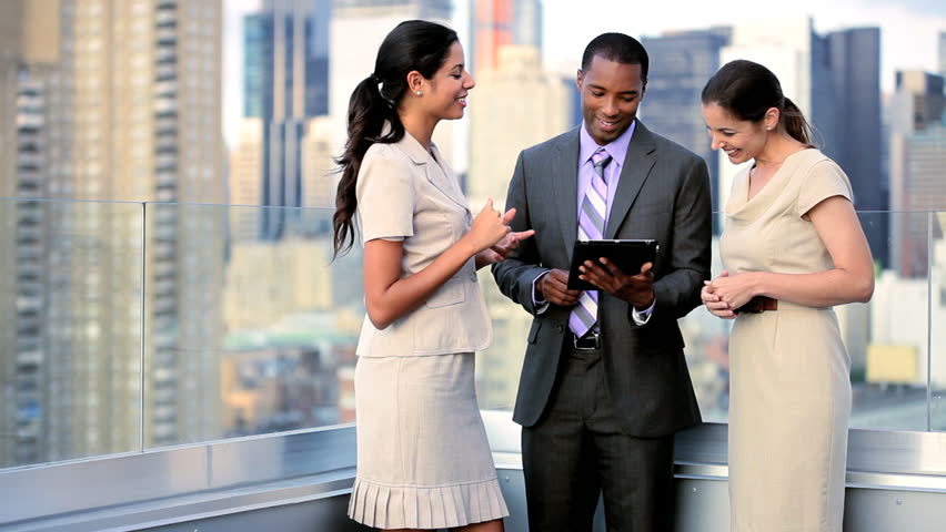 Multi ethnic female and male successful executive managers working on portfolio online touch screen on rooftop city office overlooking Manhattan
