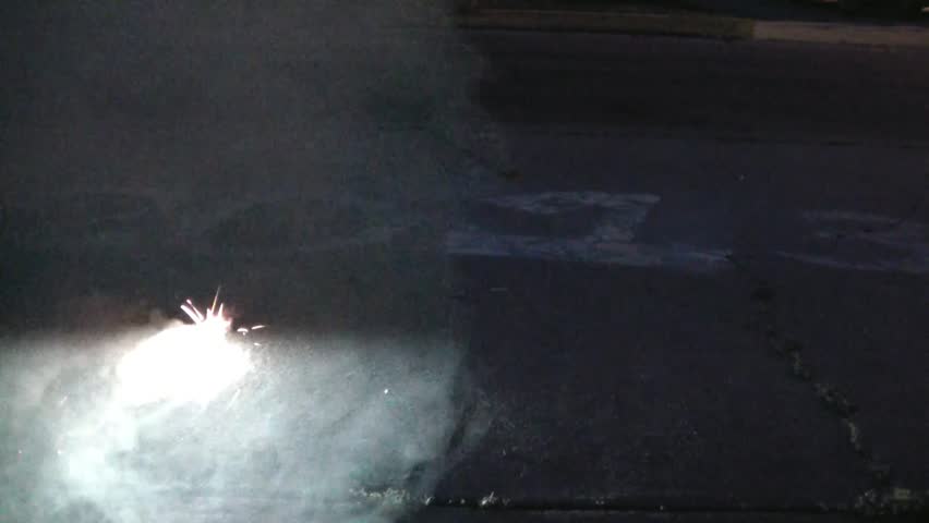 Lighting cannon firework at night in July with year '2013 written in sidewalk chalk in background.