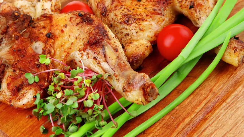 meat : grilled quarter chicken garnished with green sprouts and red peppers on wooden plate slow motion  hidef