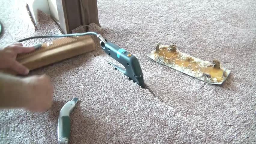 Carpet layer uses a carpet iron to heat glue for the purposes to seaming two pieces of carpet together.