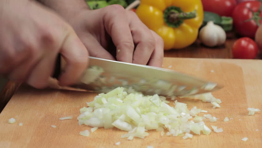 Chef cutting up an onion with a knife, tracking shot