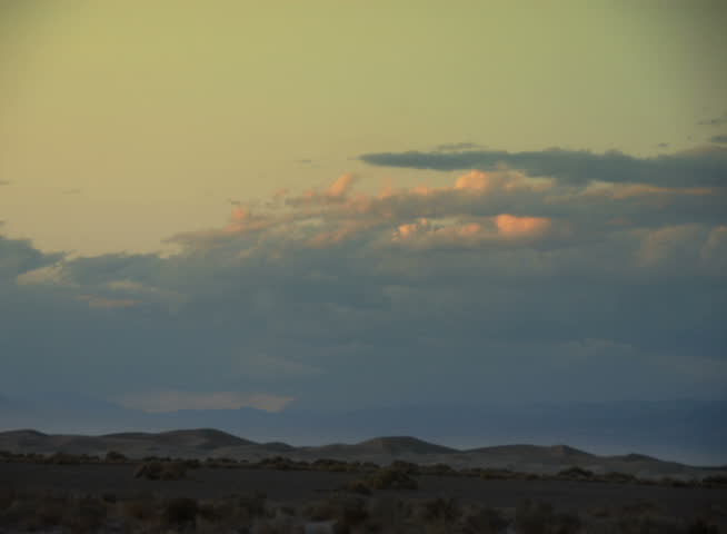 PAL - Time lapse sunsetting clouds travel over sand dunes in Death Valley National Park, California, USA.
