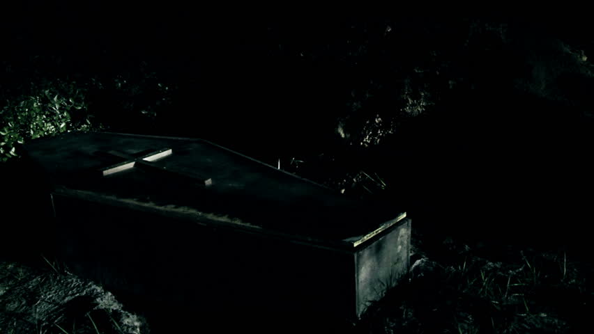 a casket in a cemetery shakes until lid of coffin reveals a spirit