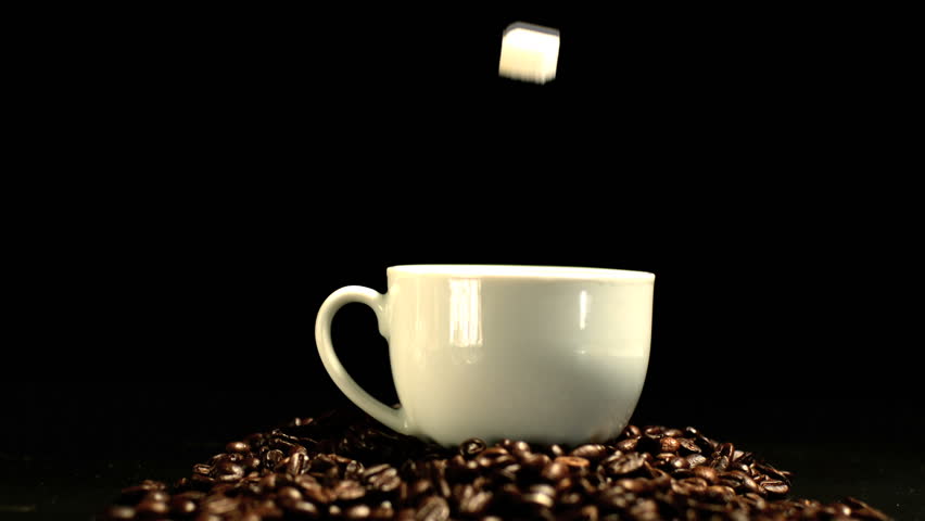 Sugar cube falling in coffee cup and splashing in slow motion