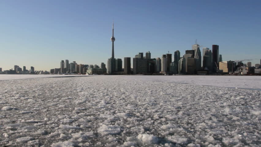 Moving wide shot of the Toronto skyline with Lake Ontario frozen over in the foreground
