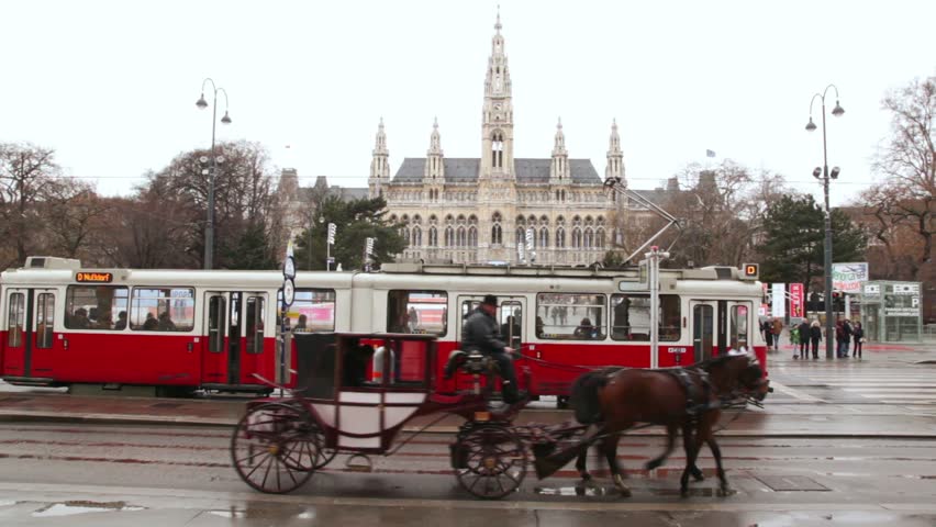 VIENNA- FEB 19: vehicle with horses passes by the tram against City Hall on Feb 19, 2011, in Vienna, Austria. In Vienna there is one of the oldest and the most extended tram network in the world.