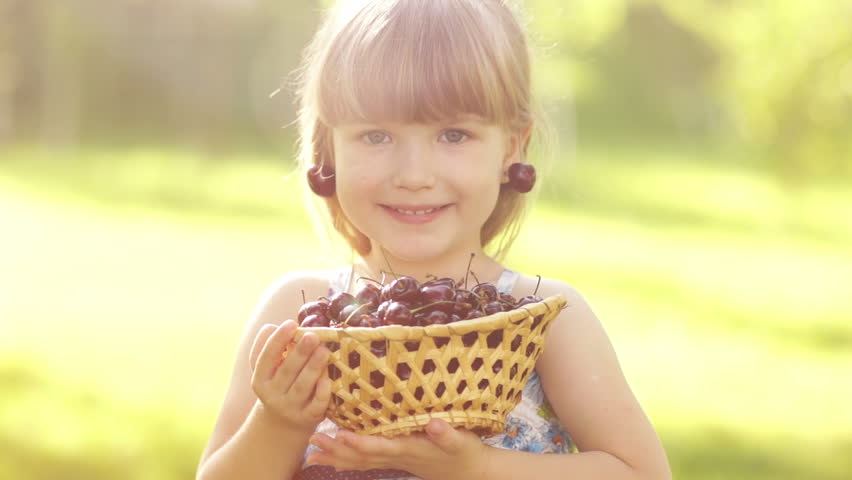 Happy child with a basket of fruit cherries. Thumbs up. Ok. Slow motion
