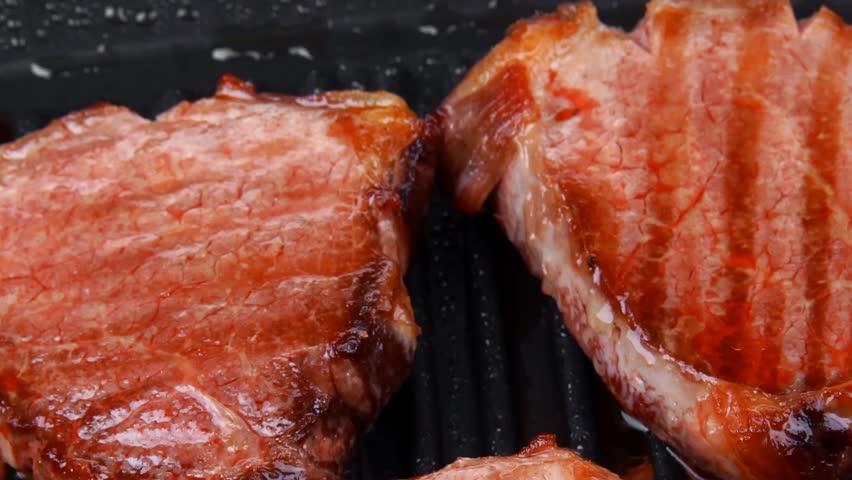 fresh grilled bloody beef steaks on black grill plate hidef slow motion intro