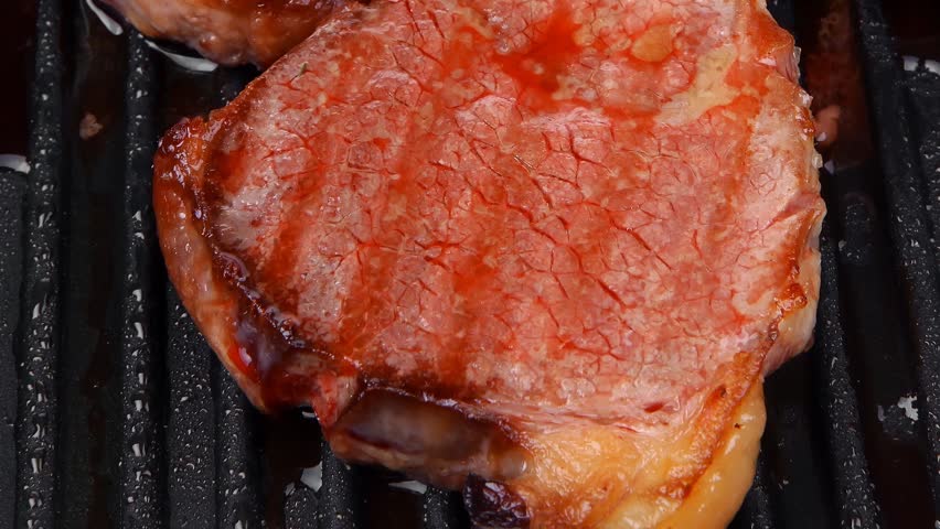 fresh grilled bloody beef steaks on black grill plate hidef slow motion intro