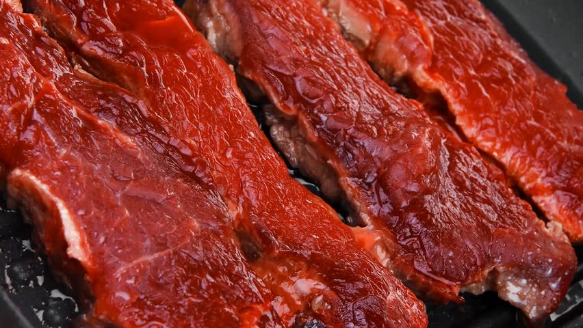 fresh raw bloody beef steaks on black grill plate hidef slow motion intro