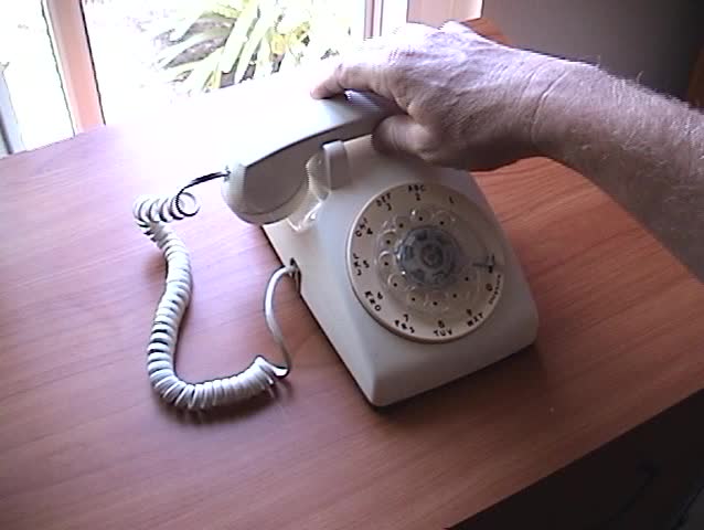 a person picks up the receiver and dials a fictitious phone number on an old rotary telephone with sound