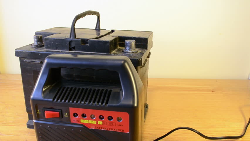 charging auto battery at home. hand put plug charger clamps on accumulator plus and minus.