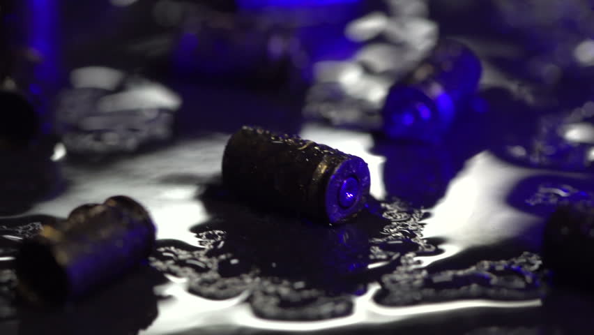 Dolly shot of 9 mm handgun bullet casings on the ground with flashing police lights