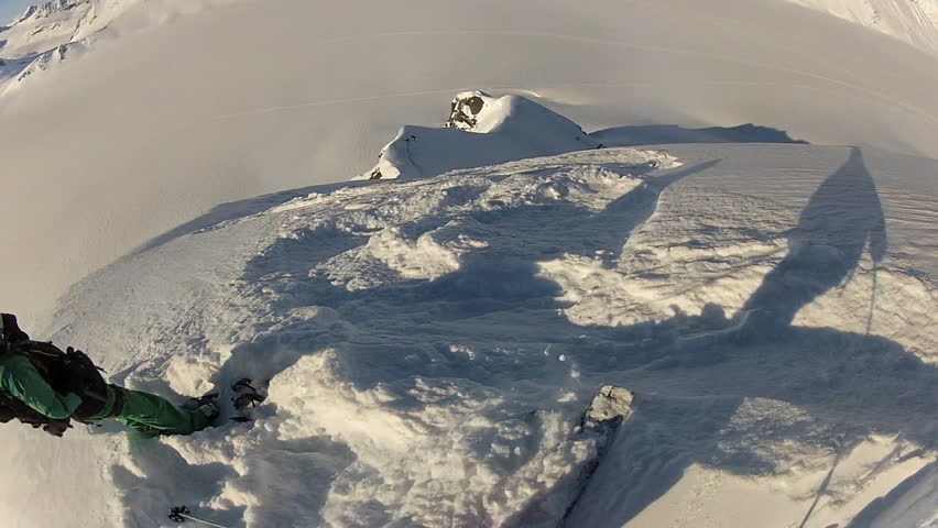 A skier carves back and forth as he rides down a mountain covered in fresh powder during the day. It is shot with a camera mounted to the athletes head and provides a POV, point of view, perspective.