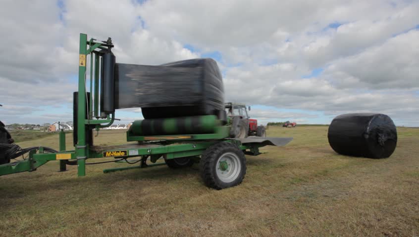 ATHENRY, IRELAND - JULY 26: Tractor wrapping bail of hay with plastic at the field on July 26, 2011 in Athenry, Ireland