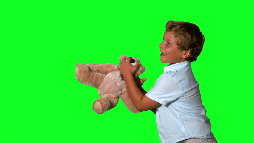 Little boy jumping and catching teddy on green screen in slow motion