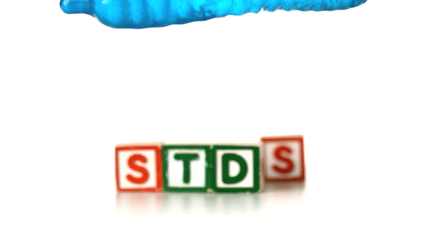 Blue condom filled with water falling and bouncing in front of blocks spelling STDs in slow motion