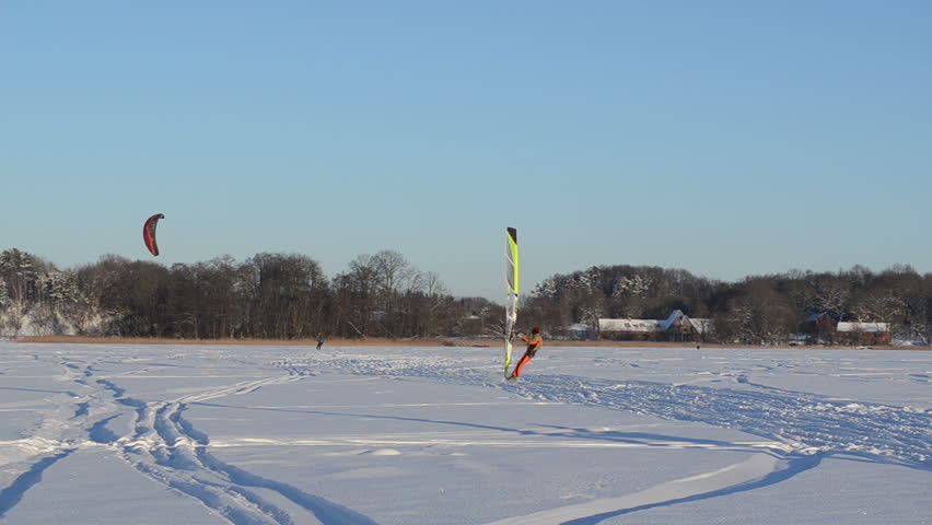 panorama view of people ice sailing surfing and kiteboarding on frozen Galves lake in Trakai amazing cold winter day.