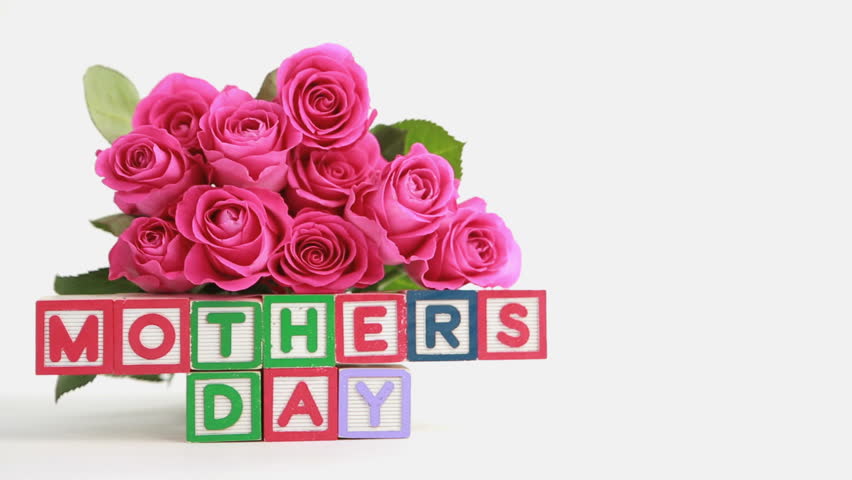 Focus on mothers day message spelled in blocks with bunch of pink roses and gift