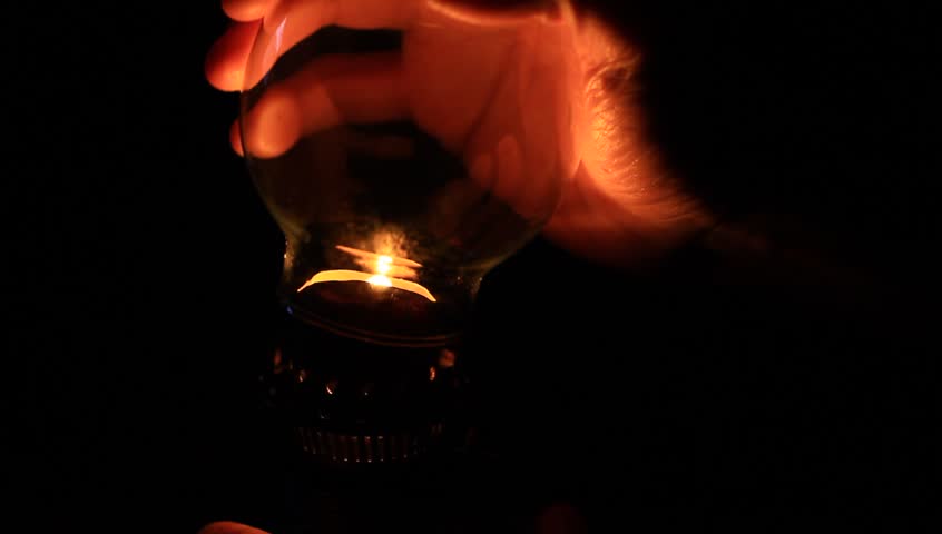 How to light an oil lamp. Light concept. Man preparing an old fashioned lantern in darkness. 
