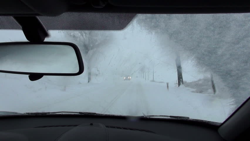 driving by car in real winter conditions, view from inside out on snow covered street. pov. 