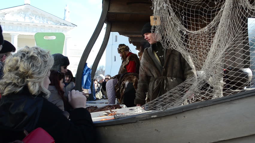 VILNIUS, LITHUANIA - MARCH 02: Customer buy fresh healthy natural fish from fisherman in wooden ship imitation in outdoor street market fair near cathedral square on March 02, 2012 in Vilnius.