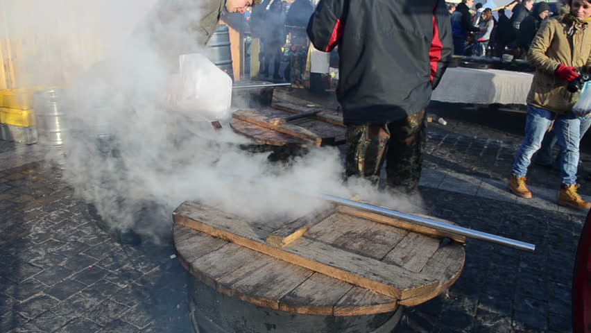 VILNIUS, LITHUANIA - MARCH 02: Man pour wine from plastic tank in big pot and people buy alcohol in spring outside street market fair on March 02, 2012 in Vilnius. Vapour rise from boiling wine.