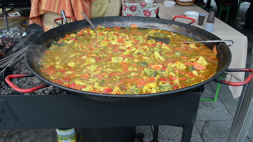 Healthy diet food vegetable stew in huge hot pan and fresh meat bake on fire in outdoor street event.
