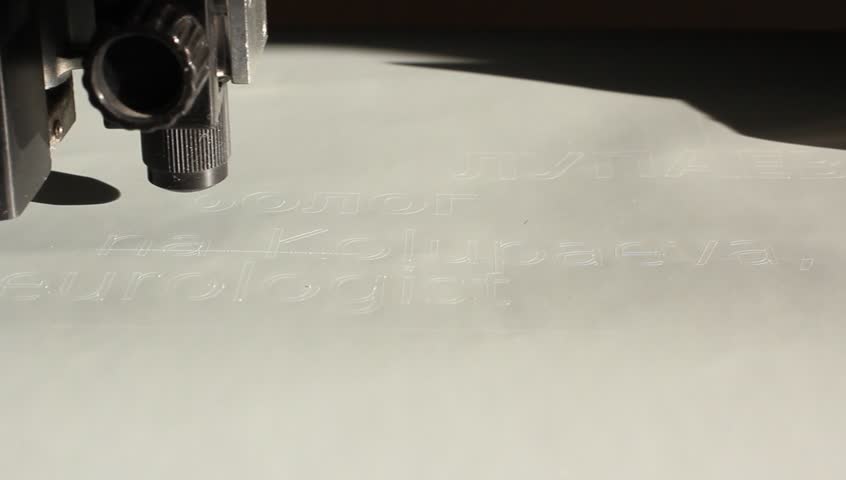 Cutting plotters use knives to cut the letters on gray vinyl film. Top view closeup