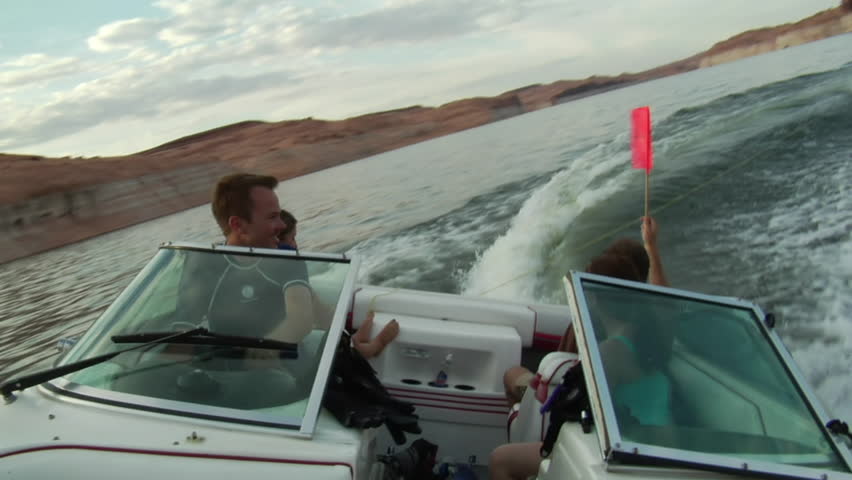 Young people drive ski boat and turns sharply