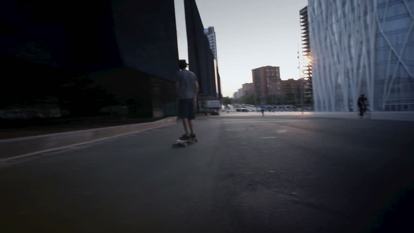 Young guy with skateboard on urban hill during a nice sunset