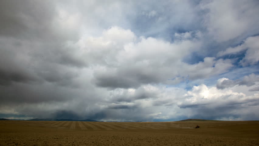 Time Lapse of Clouds and Tractor Harrowing Field	