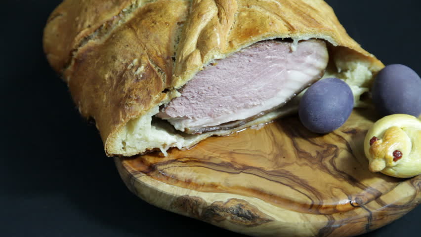 Rotating food series: Delicious ham baked in bread dough with Easter decoration, on olive tree plate, series of Easter baked ham