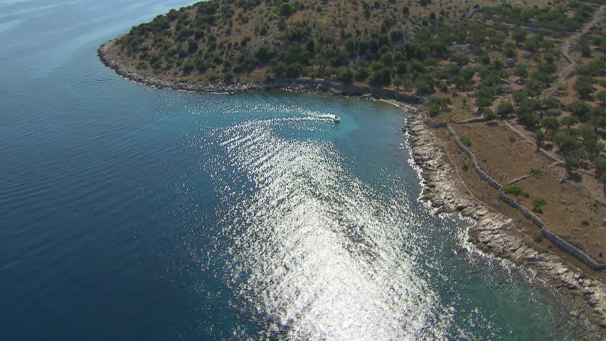 A desolate beach belonging to Kornati archipelago, calm sea and a boat. Aerial helicopter shot.