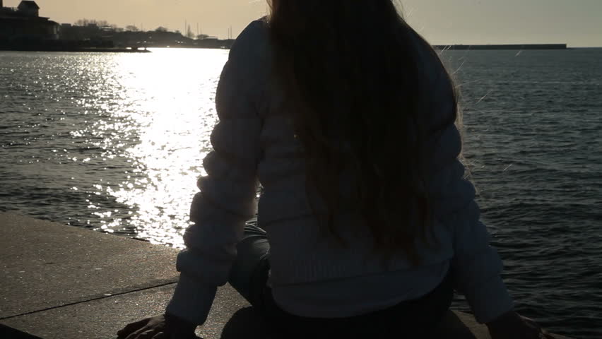 Little girl sitting on the embankment at sunset Sevastopol