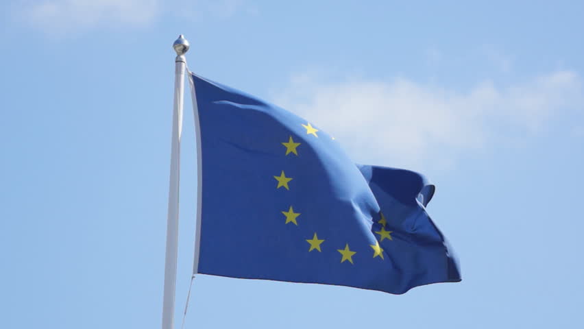 European union flag blowing a strong wind against a blue sky