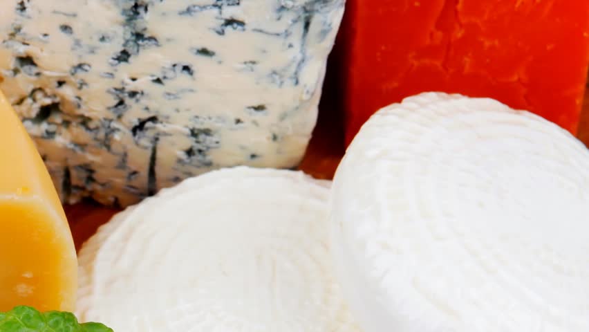 delicatessen french cheese on wooden board with hot peppers and dill 