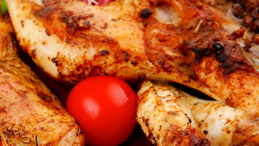 roast meat : chicken legs garnished with green sprouts and peppers on wooden plate isolated over white background