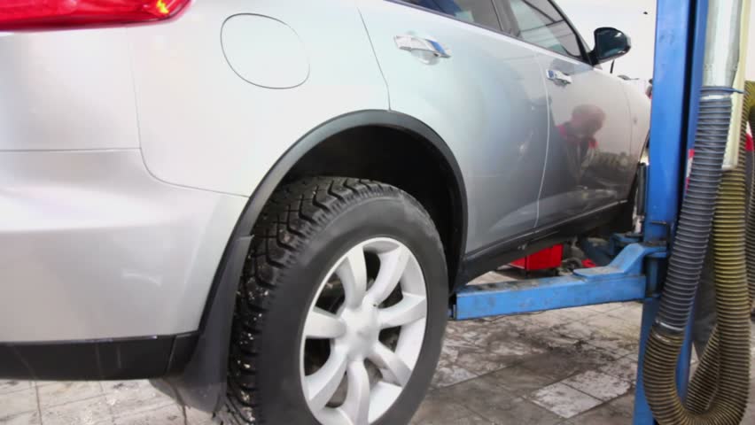 Man lifts offroader by elevator in car service center, closeup