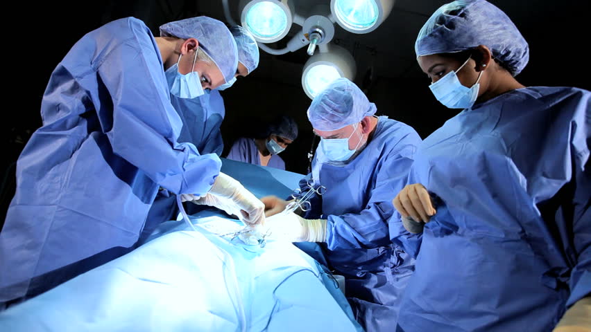 Doctor Wearing Protective Clothing Performing Surgery Using Sterilised