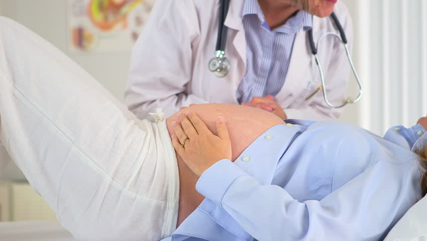 Doctor putting hands on pregnant woman's belly
