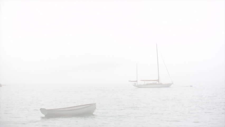 sailboat and dinghy at sea with fog