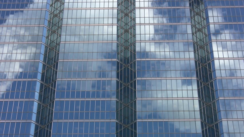 Office windows reflect steam from a large chimney.