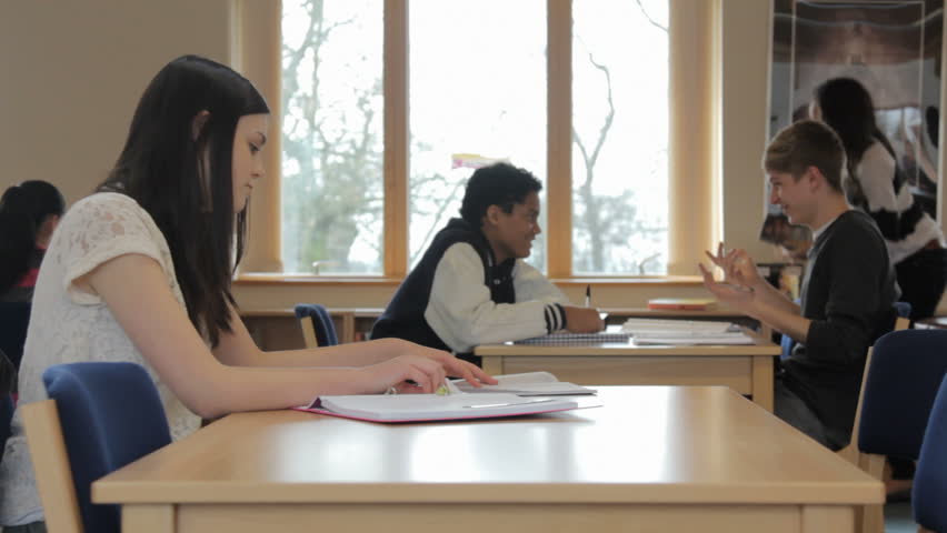 Teenage boy and girl flirting - in school library