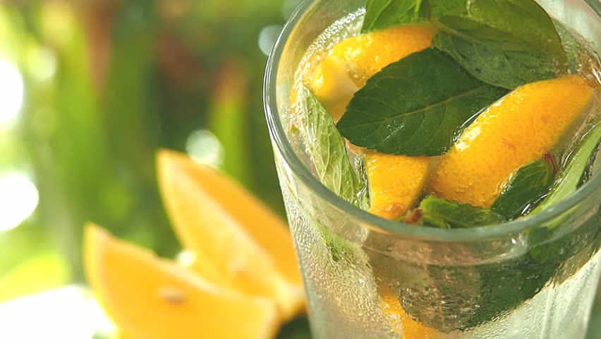 a glass with lemon, mint and ice cubes