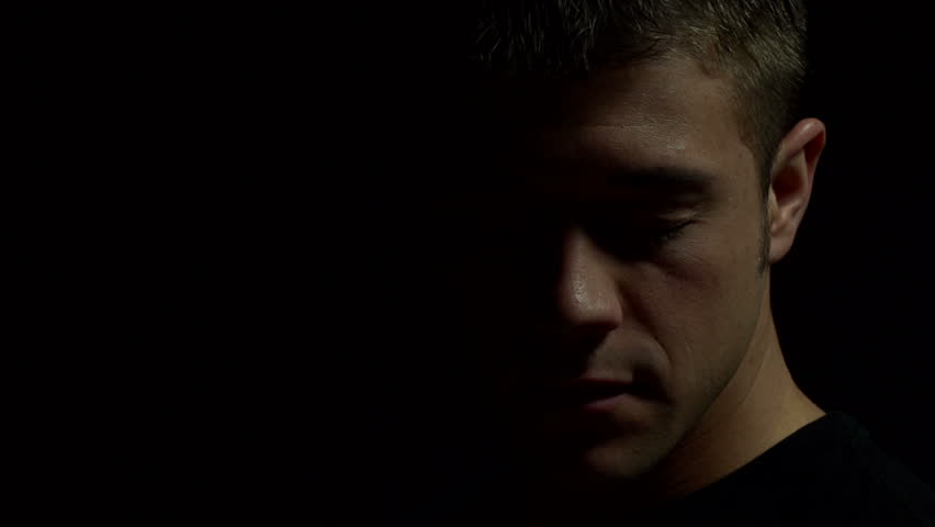 Man facing down with eyes closed in color. Experimental lighting.